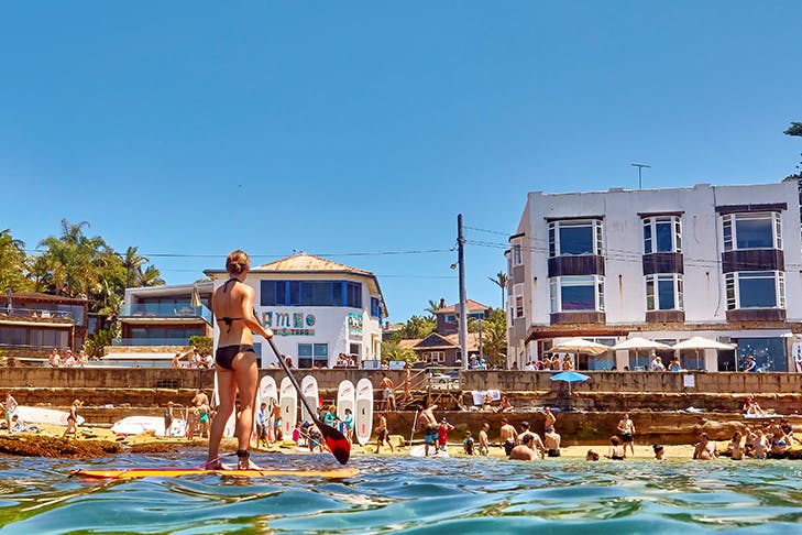people swimming and paddling in small beach enclave